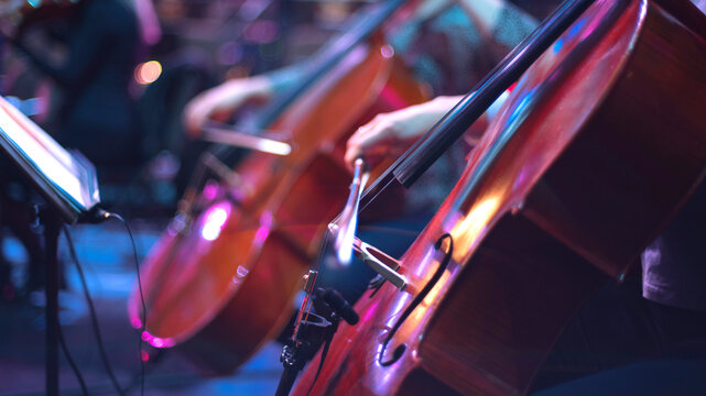 girl playing cello in orchestra on stage