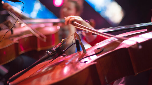 girl playing cello in orchestra on stage