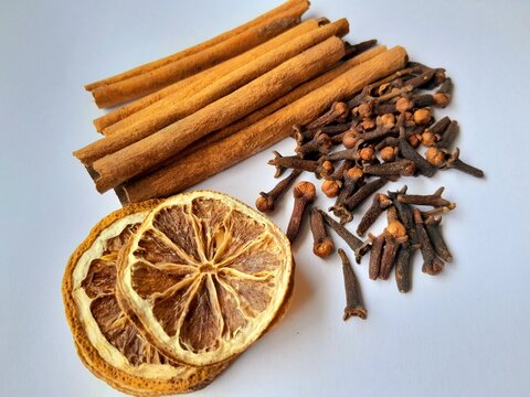 dried sliced lemon, cloves and cinnamon sticks on white