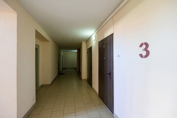 long, tiled hallway with doors and beige walls. The number 