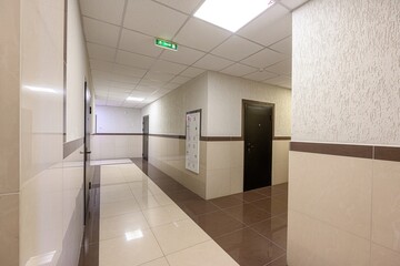 bright, tiled hallway with dark doors and an exit sign, giving a clean, modern look