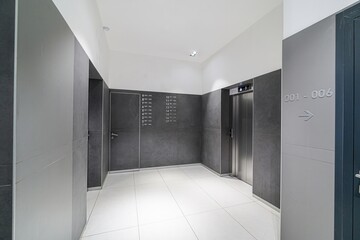 modern hallway with white tile floors, gray walls, an elevator, and apartment numbers