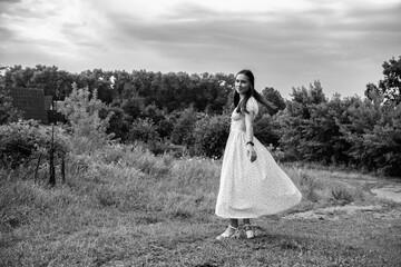 Portrait of a young beautiful dark-haired girl in a dress in the forest. Vintage black and white...