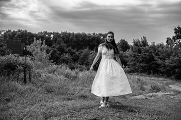 Portrait of a young beautiful dark-haired girl in a dress in the forest. Vintage black and white...