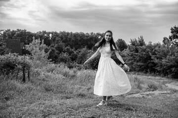 Portrait of a young beautiful dark-haired girl in a dress in the forest. Vintage black and white...