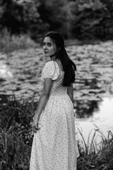 Portrait of a young beautiful dark-haired girl in a dress in the forest. Vintage black and white...