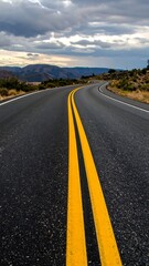 Naklejka premium Winding asphalt road under a cloudy sky