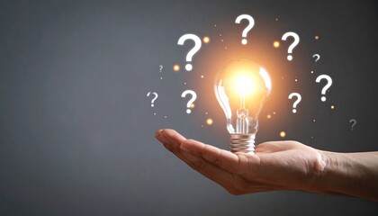 glowing lightbulb held by hand surrounded by floating question marks on dark background