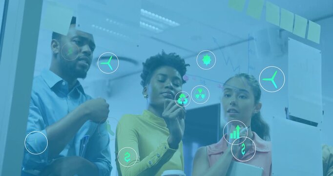 Team placing sticky notes on glass board activating energy icons mapping eco metrics