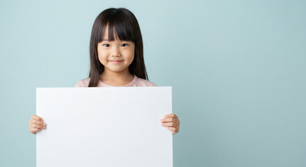 Young girl holding a blank sign against a light teal backdrop.