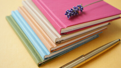 Stack of colorful notebooks with a pen and decorative ribbon