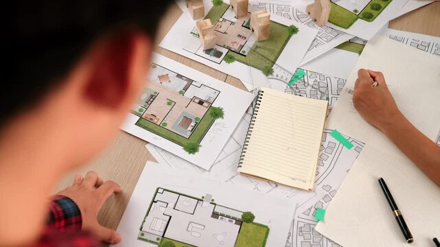 Architect and engineer consider or discuss about building construction using blueprint on table with architectural document, measurement tool and wooden block scatter around at office. Delineation.