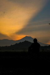 Fototapeta premium Contemplative silhouette against mountain dawn