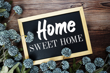 Home Sweet Home text on blackboard with flowers decoration on wooden background
