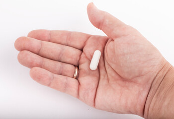 a capsule with medicine in the palm of an elderly woman
