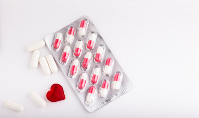 Multicolored capsules in a blister pack, and white capsules with medicine on a white background