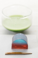 Cup of fresh matcha tea, green tea and Kingyoku can, traditional Japanese jelly confectionery on white wooden table.