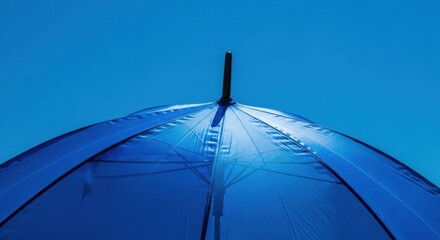 A close up view of a blue umbrella against a clear blue sky on a bright and sunny day outdoors
