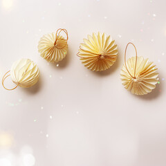 Minimal style winter holidays top view composition with New Year paper festive ornaments cream beige Christmas balls on light gray or white background, light effects, copyspace. Neutral tones
