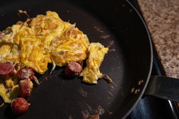Scrambled Eggs and Sliced Hot Dogs Cooking in a Frying Pan