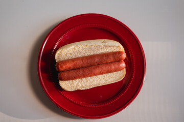 Two Plain Hot Dogs in one Bun on a Red Plate