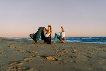 Couple Practicing Yoga on the Beach at Sunset