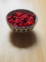 Fresh Raspberries in a Decorative Bowl on Wooden Table, Vertical Closeup 