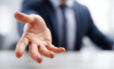 Close up of hands reaching out to grab something, business man in suit with open hand gesture for making offer or offering on office desk.