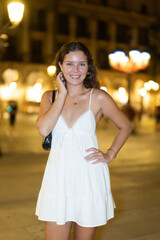 Fototapeta premium Relaxed woman after dinner in a restaurant walking around the evening city, she came on vacation to Spain and goes on dates