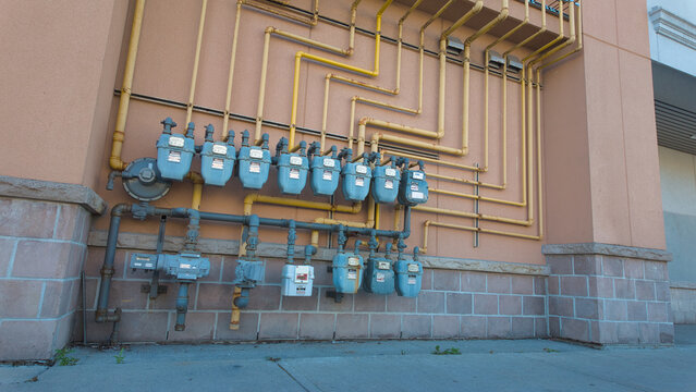 Industrial gas meters and yellow pipes on a building wall, displaying intricate patterns and connections.