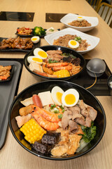 A hearty bowl of seafood noodle soup filled with shrimp, corn, egg, vegetables, rice blood cake, tofu skin, and assorted hotpot ingredients. The colorful ingredients float in a rich broth, making for 