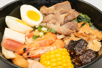 A hearty bowl of seafood noodle soup filled with shrimp, corn, egg, vegetables, rice blood cake, tofu skin, and assorted hotpot ingredients. The colorful ingredients float in a rich broth, making for 