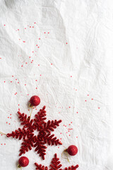 Top view christmas themed decoration on paper texture background. Red decoration snowflake and decoration ball.
