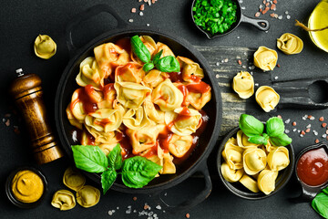 Ravioli with tomato sauce and basil on a dark background. Top view. Italian traditional cuisine.