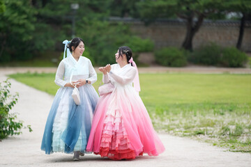 In Seoul in June 2025, two Korean women in their twenties wear pink and sky-blue hanbok as they...