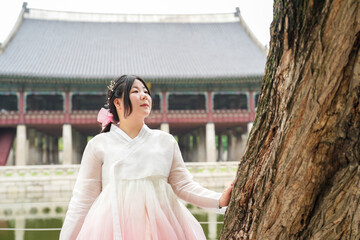In June in Seoul, a Korean woman in her twenties stands beside a wooden pillar at Gyeongbokgung...