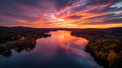 Obraz premium Vibrant Sunset Reflection Over Calm Lake Surrounded by Autumn Trees