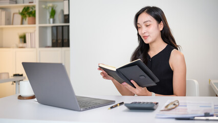 Confident businesswoman reading notes during virtual meeting at modern office desk.