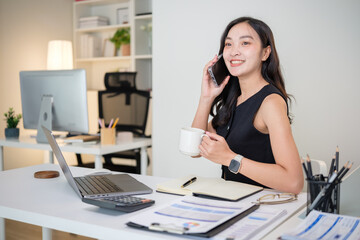 Smiling businesswoman having a phone conversation while working at her desk.
