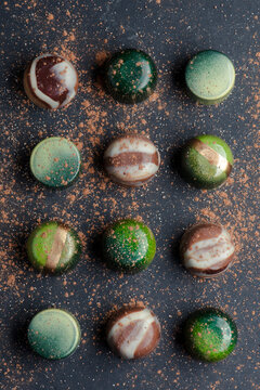 Colorful chocolate bonbons arranged neatly on a dark surface, showcasing intricate designs and textures indicative of fine confectionery craftsmanship