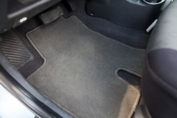 Clean car floor mats of black carpet under front passenger seat in the workshop for the detailing vehicle before dry cleaning. Auto service industry. Interior of sedan.