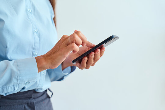 Businesswoman Browsing Smartphone In Light Blue Shirt And Office Attire, Engaging In Online Communication, Conceptualizing Productivity, Focus, Technology Usage, Modern Work Environment.