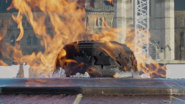 Extreme close-up of the Centennial Flame at Canada's Parliament Hill, Ottawa, capturing its vibrant flames against a historic architectural backdrop.