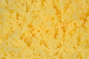 A close-up, full-frame shot captures the textured appearance of a heap of light yellow, finely mashed potato pieces