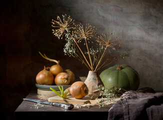 Still life with onions, dry bouquet and pumpkin on a dark background