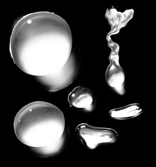 Close up macro photography of clear liquid droplets and splashes reflecting light on a dark surface...