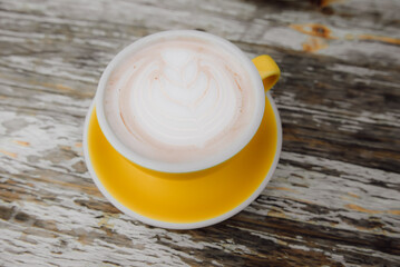 Top view of latte on a yellow tray on a classic wooden table.
