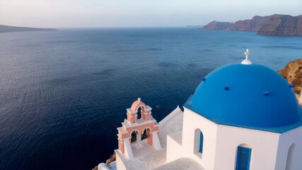 Revealing the Iconic Blue Dome Church of Oia, Santorini, with a Sweeping View of the Aegean Caldera.