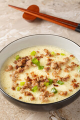 Steamed Eggs with Crispy Pork and green onion closeup in the bowl on the table. Vertical