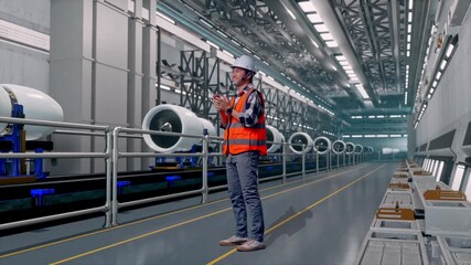 Full Body Side View Of Asian Male Engineer With Safety Helmet Smiling And Clapping His Hands While Standing, Aircraft Engine Manufacturing and Assembly Line in a Modern Factory - Powered by Adobe